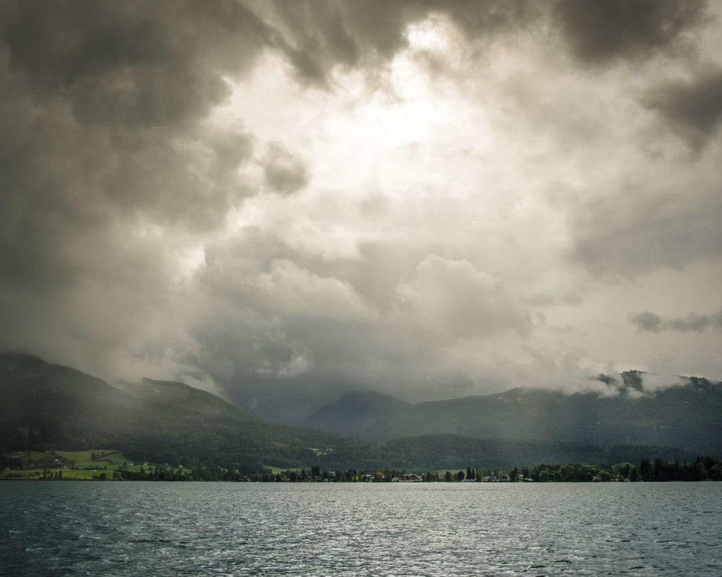 Stormy weather over Wolfgangsee with rays of sunshine protruding through the clouds