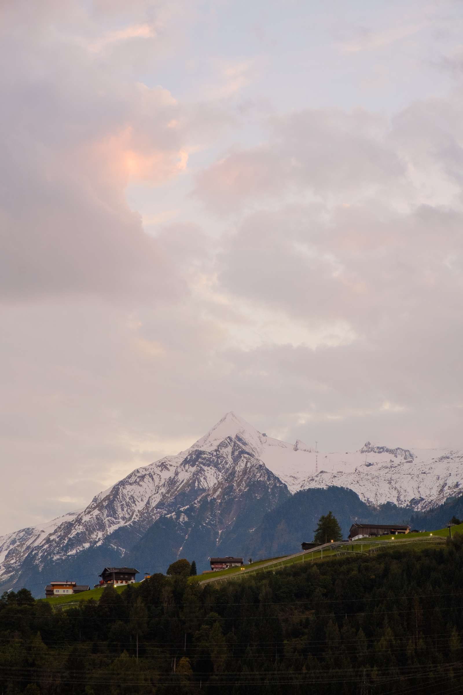 Pink fluffy sunset over Kitzsteinhorn with wooden houses in the foreground