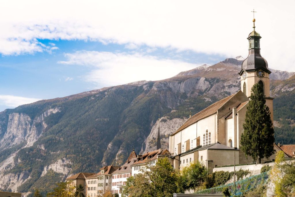 A line of buildings leading down from the Church with mountains in the background