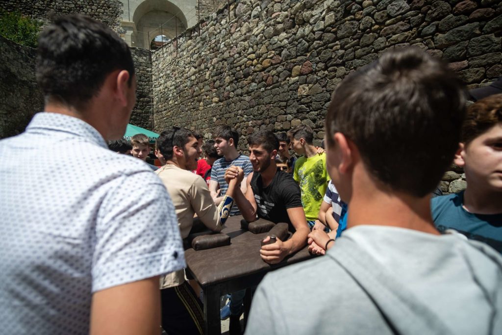 Young men doing arm-wrestling during independence day, Rabati Castle, surrounded by people cheering them on