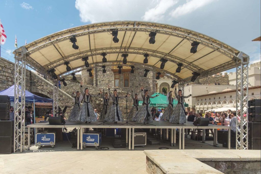 Young women dressed beautifully with long braids performing a traditional dance on stage at Rabati Castle, Akhaltsikhe