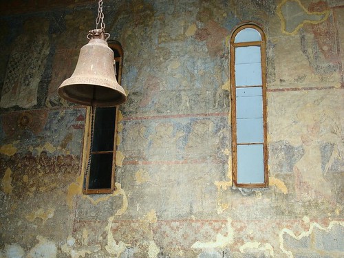 Bell in Vardzia Church of Assumption with frescoes in the back