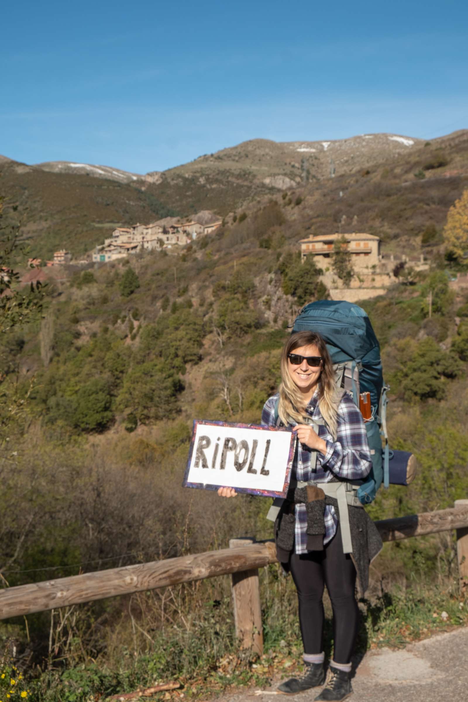 Caroline holding the hitchhiking sign on Catalonia outside of Castellar de n'Hug