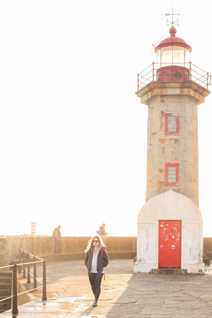 Caroline walking away from lighthouse backlit by the sun