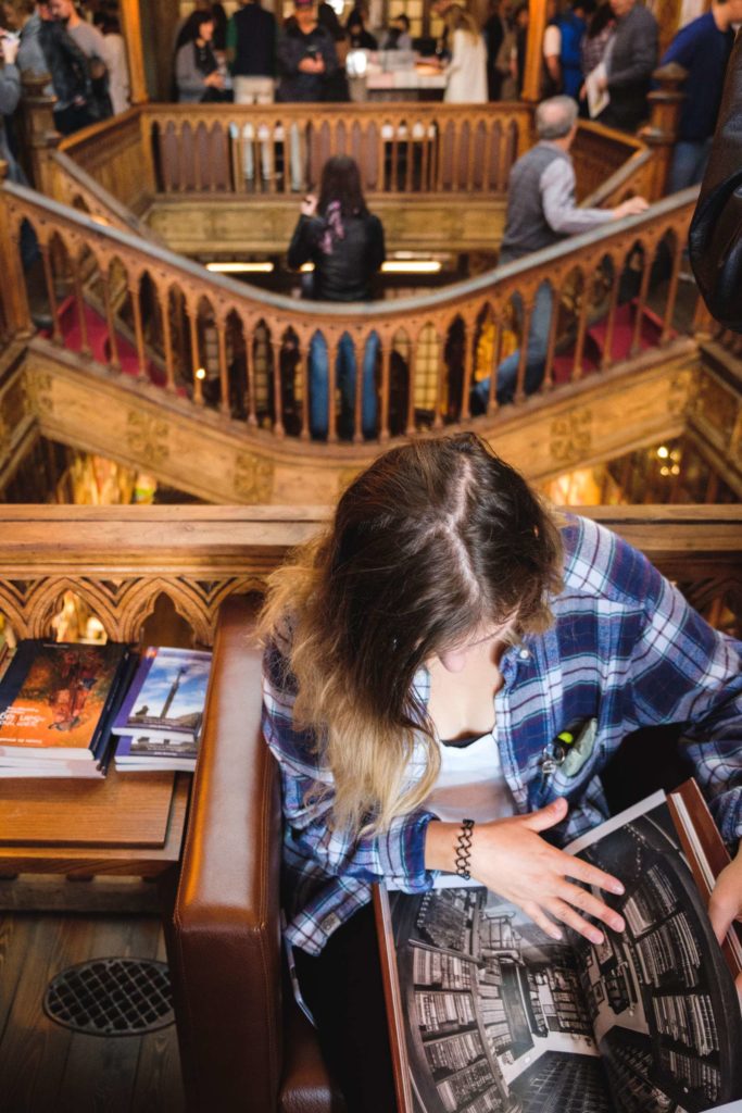 Caroline reading book in Livraria Lello