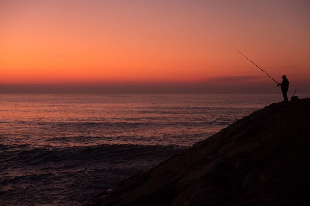 Lone fisherman in sunset at Costa Nova beach