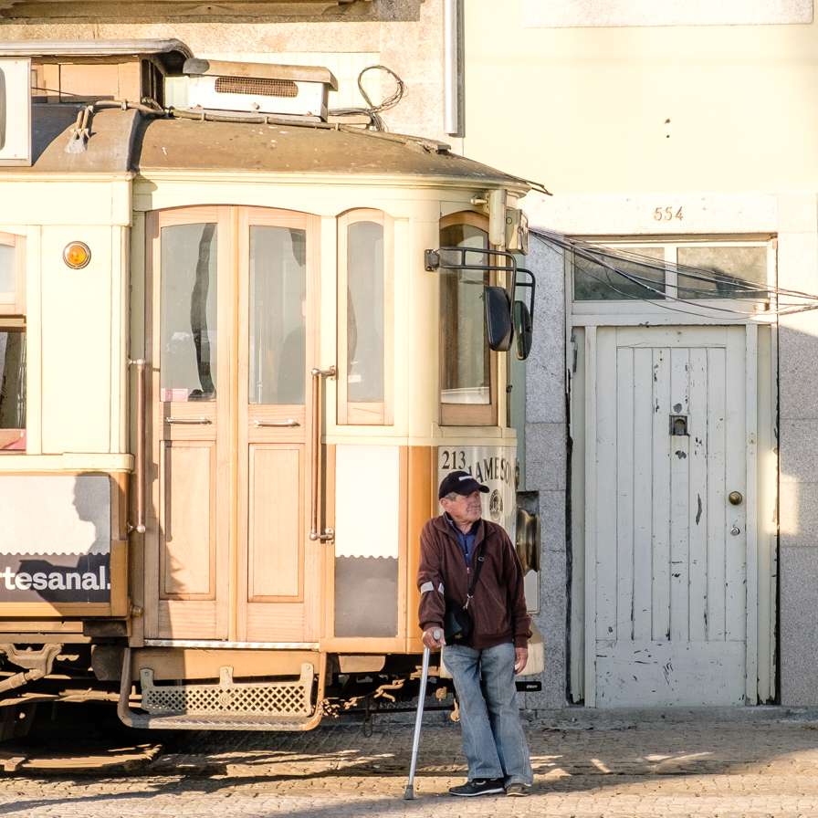 Old man leaning against a tram in Porto