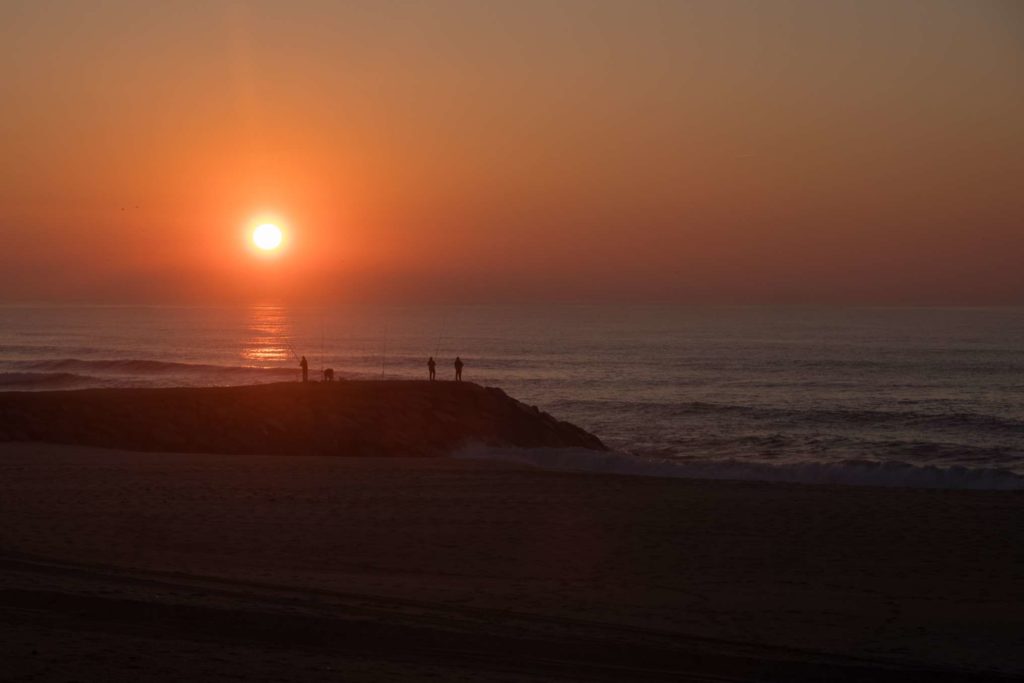 Silhouettes of fisherman with burning sun behind