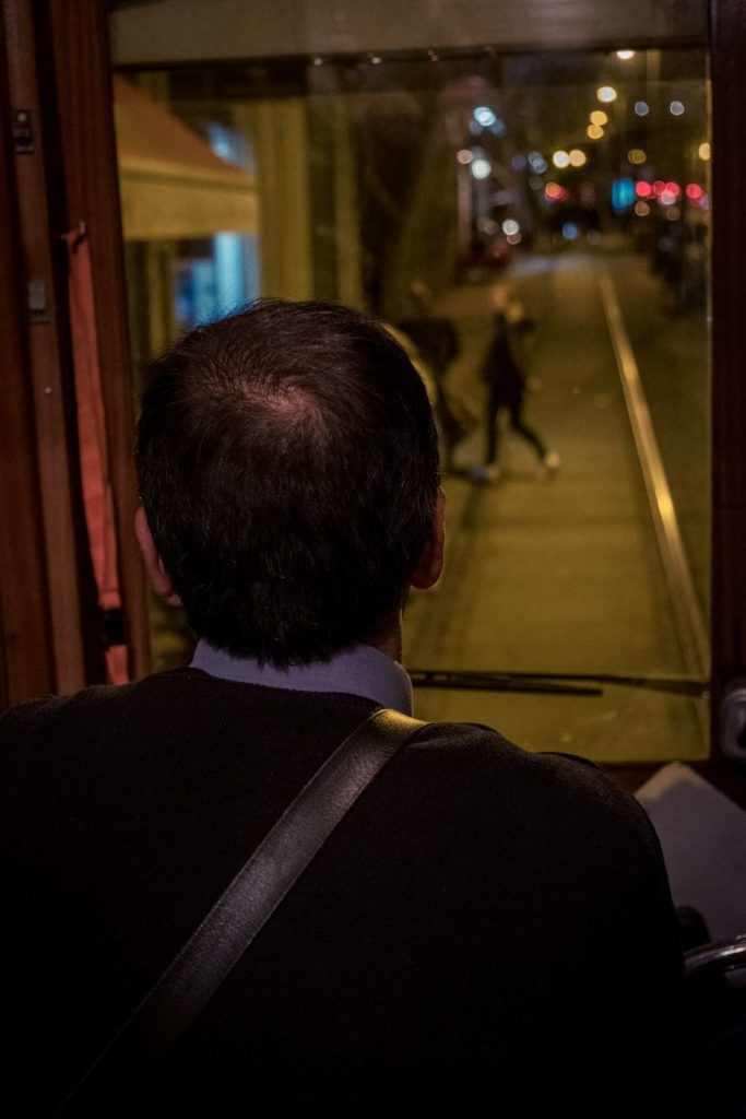 Tram driver with people on the street moving out the way