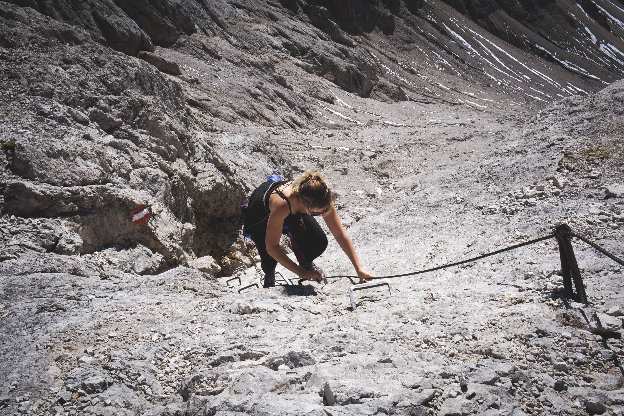 Caroline climbing on pegs with cables on Dachstein