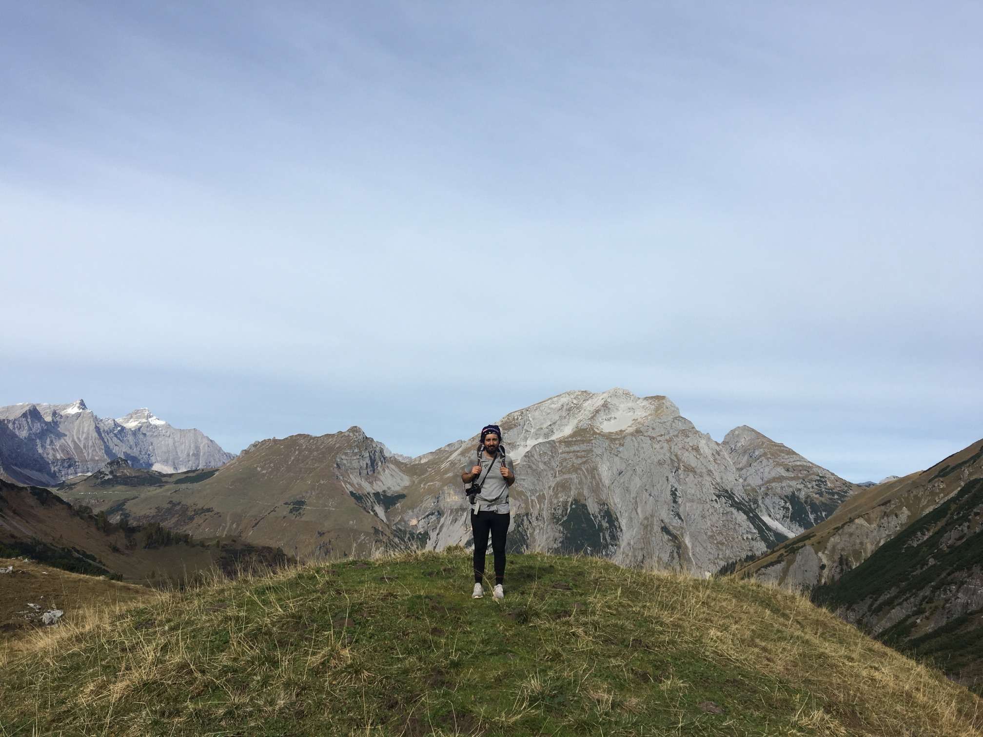 Aydin standing at the highest point of the day surrounded by mountain peaks