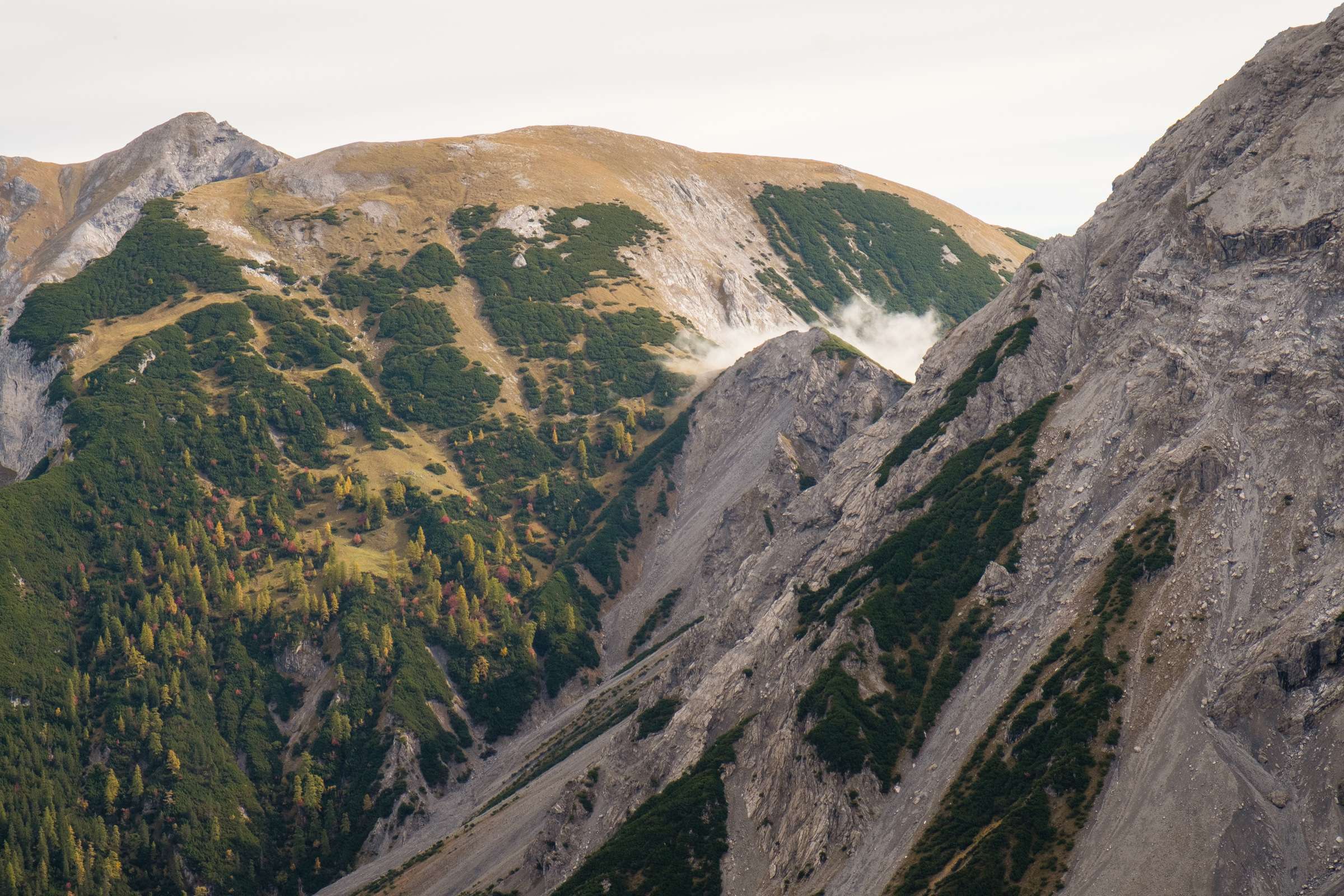 Clouds rolling over the peaks, autumnal forests lining the peaks