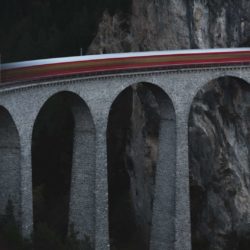 A blurred long exposure photo of a train going across the Landwasser Viaduct on the Glacier Express