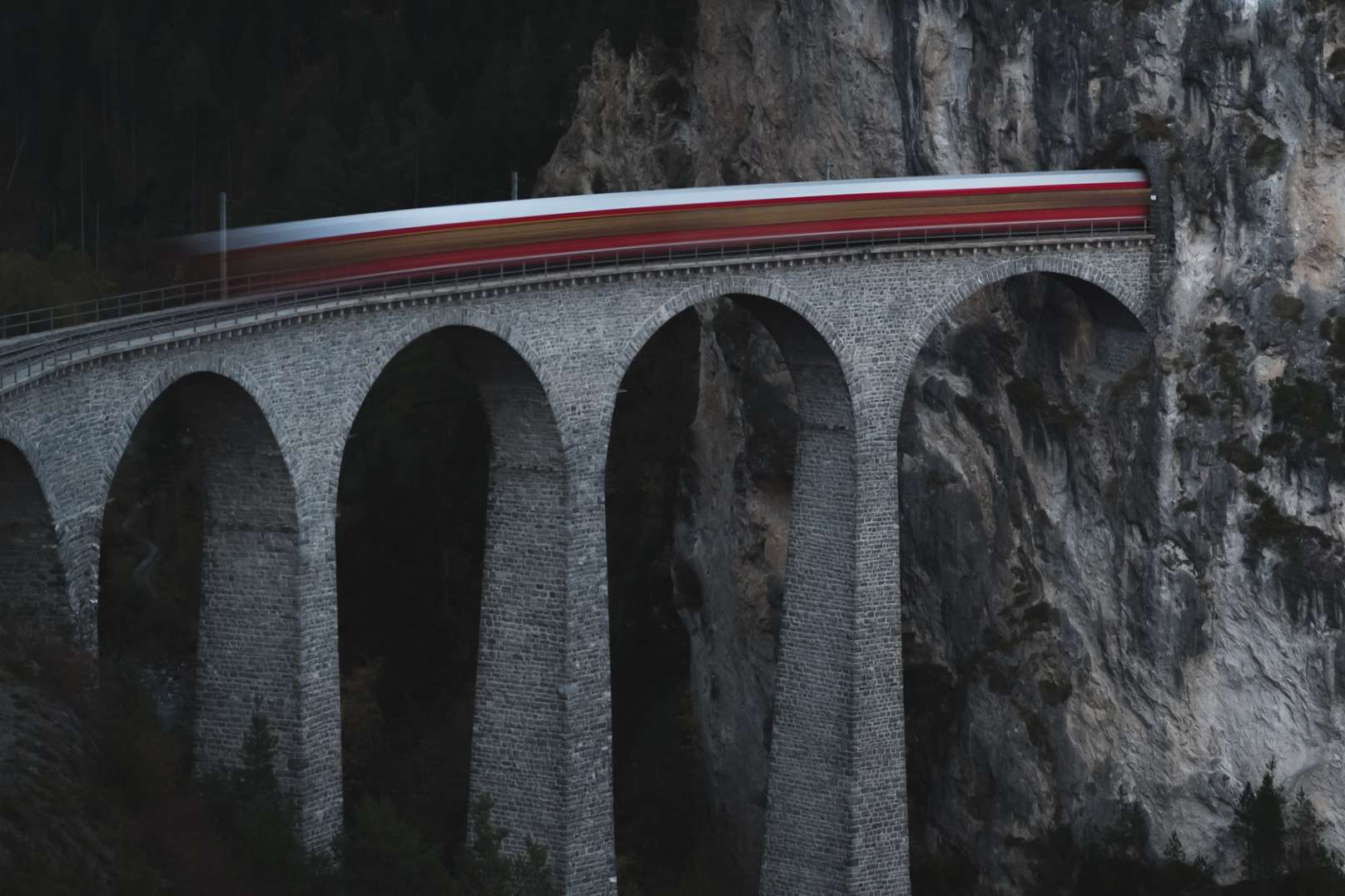 A blurred long exposure photo of a train going across the Landwasser Viaduct  on the Glacier Express