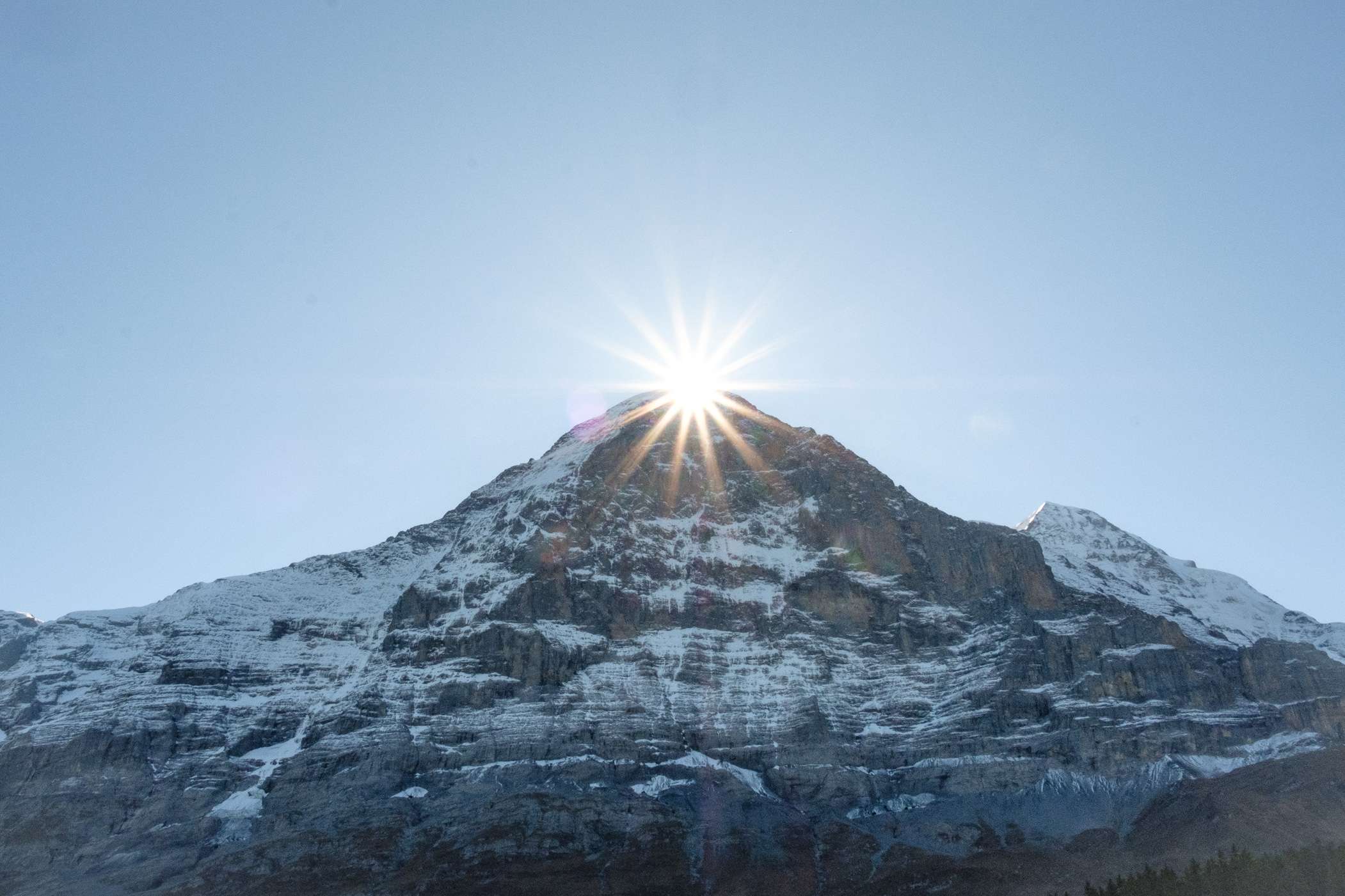 The sun peeking over the top of a mountain