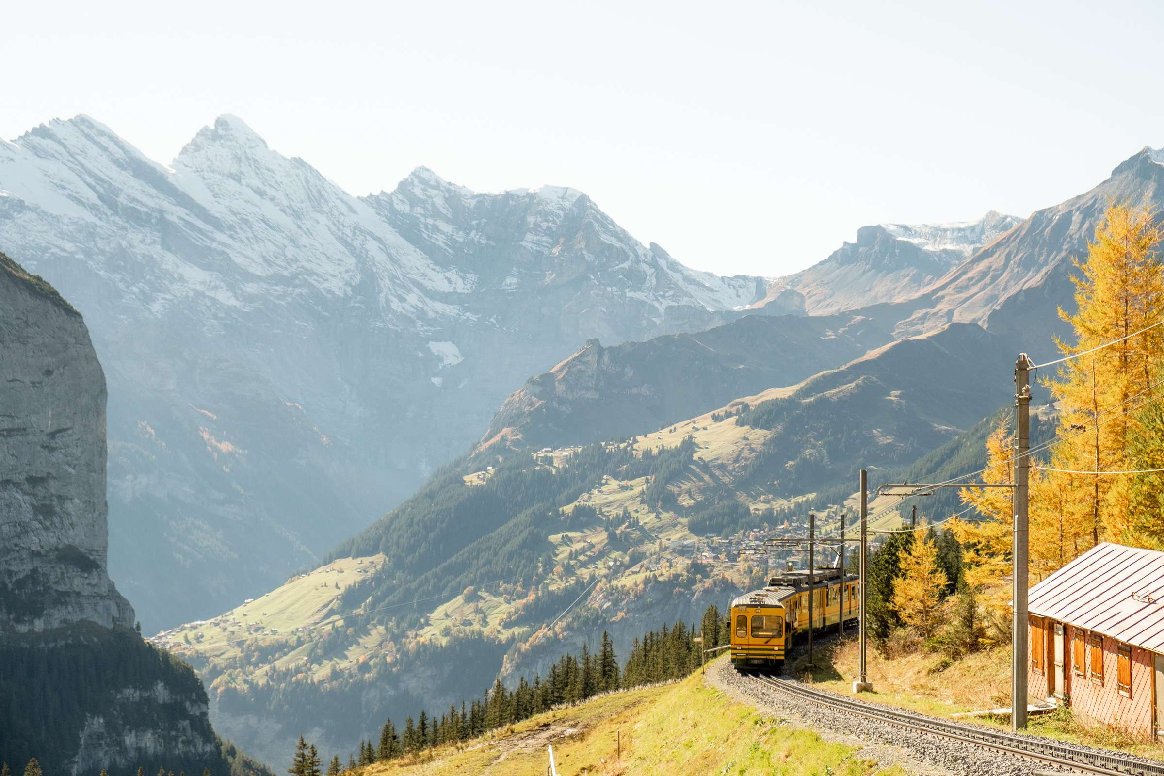 A yellow green train on the railway from Wengen to Kleine Scheidegg