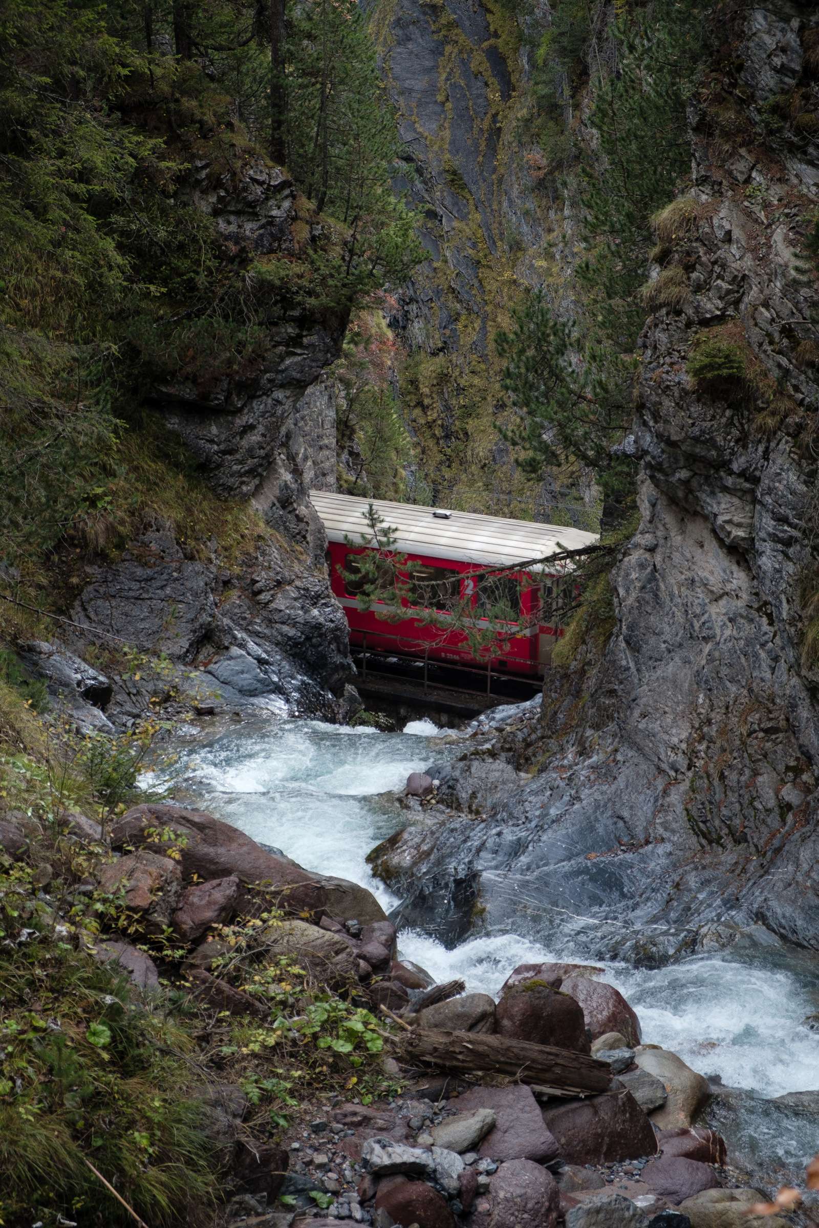 Train tracks passing over a waterfall complete with train on the Glacier Express