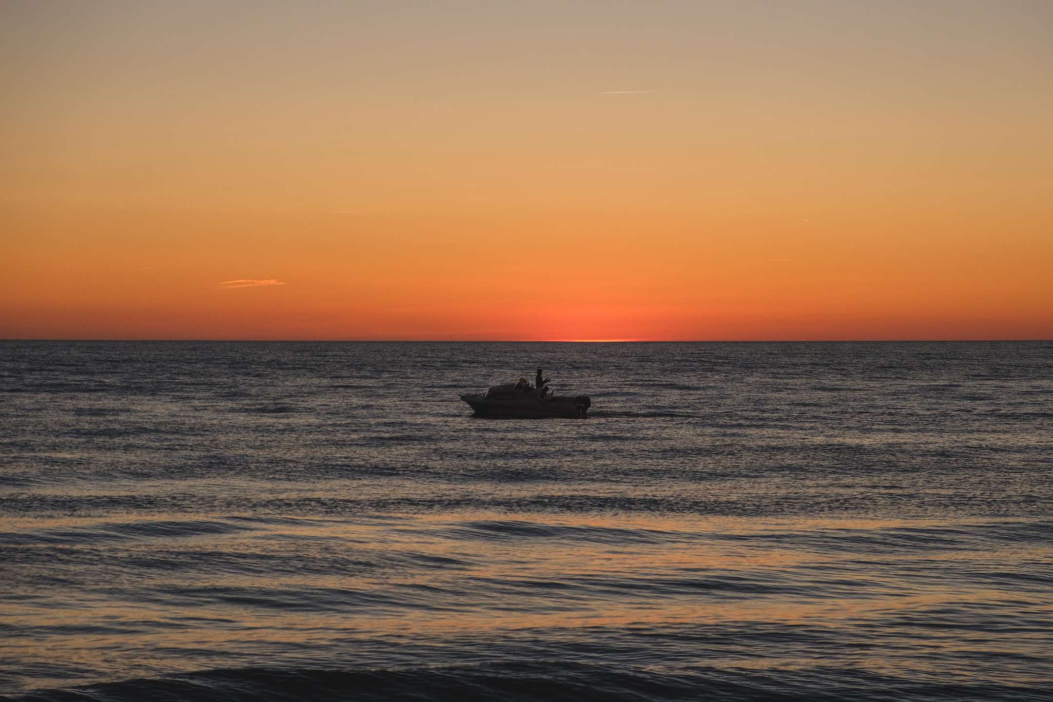 A fisherman in the sea with fiery sky