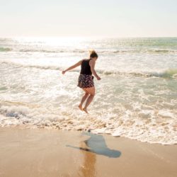 Caroline jumping in the water on the beach