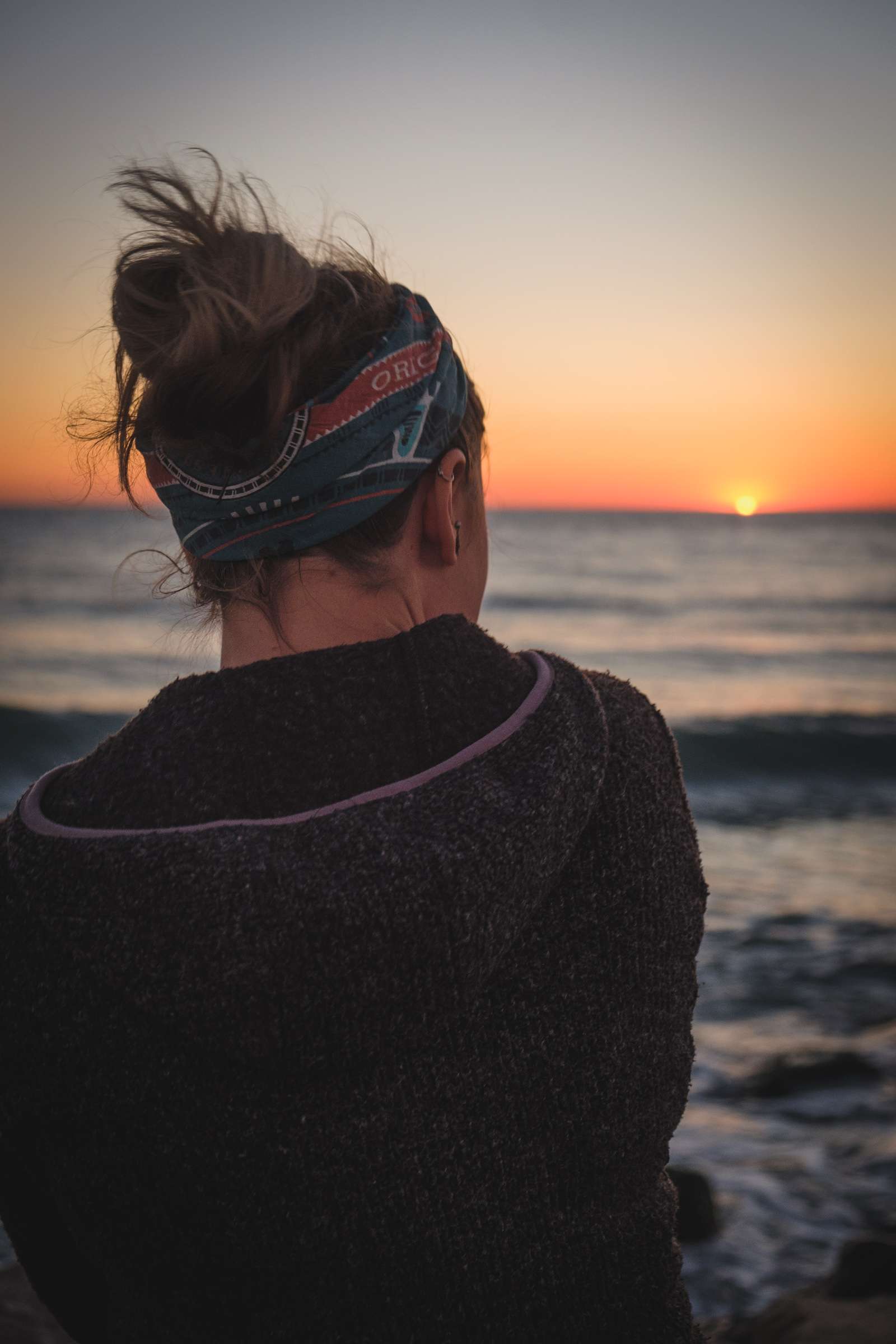 Caroline watching the sea with out of focus sunset