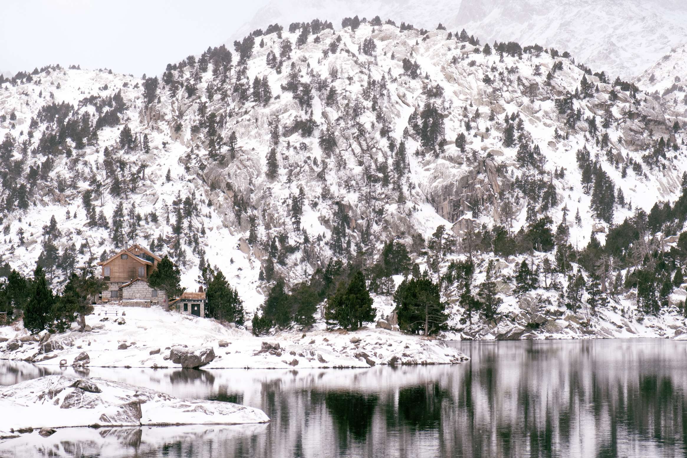 Refugi Josep Maria Blanc at lake Trullo with snowy mountains in the background