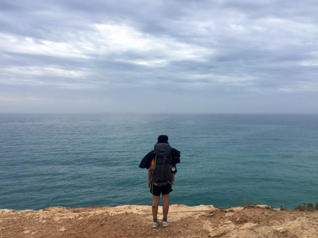 Aydin standing on edge of Algarve cliffs looking out to the Atlantic ocean