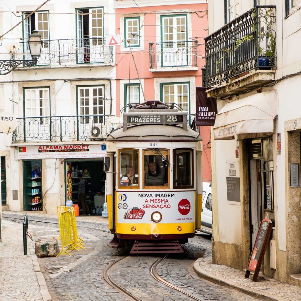 Cute yellow tram in a tight spot in Alfama, Lisbon