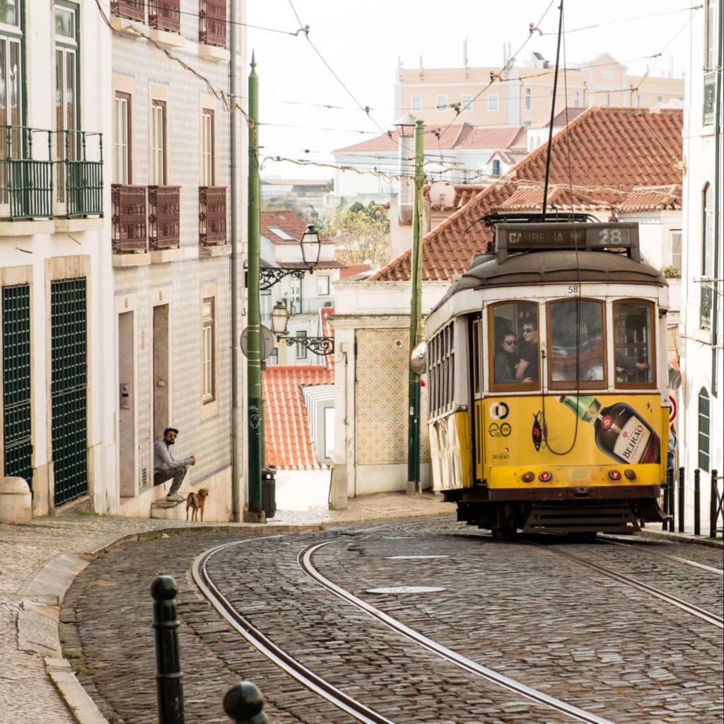 Cute yellow tram on cobbled street in Alfama, Lisbon