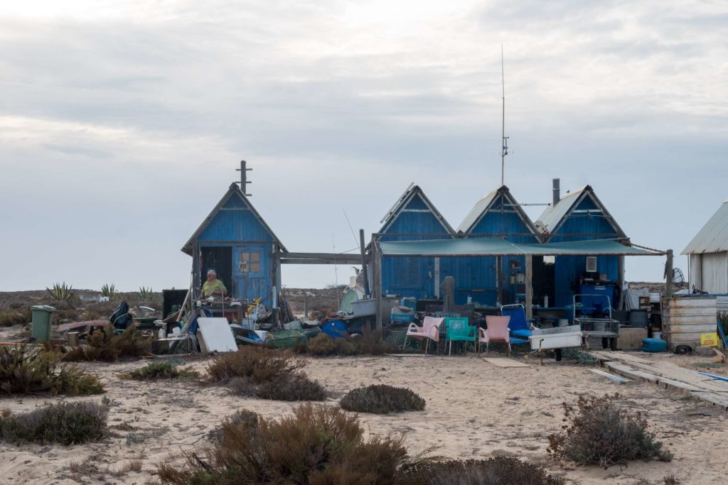 Man in wooden huts at Ilha Deserta (Deserted Island)