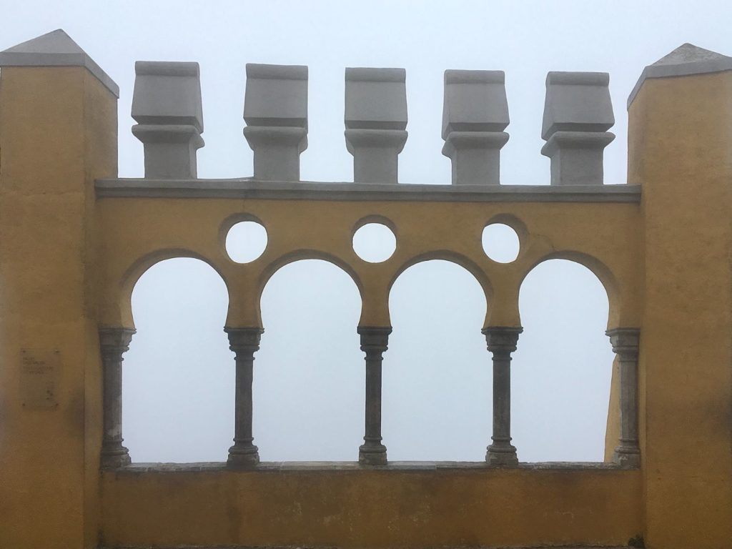Yellow arched walls of Pena Palace looking out to thick fog