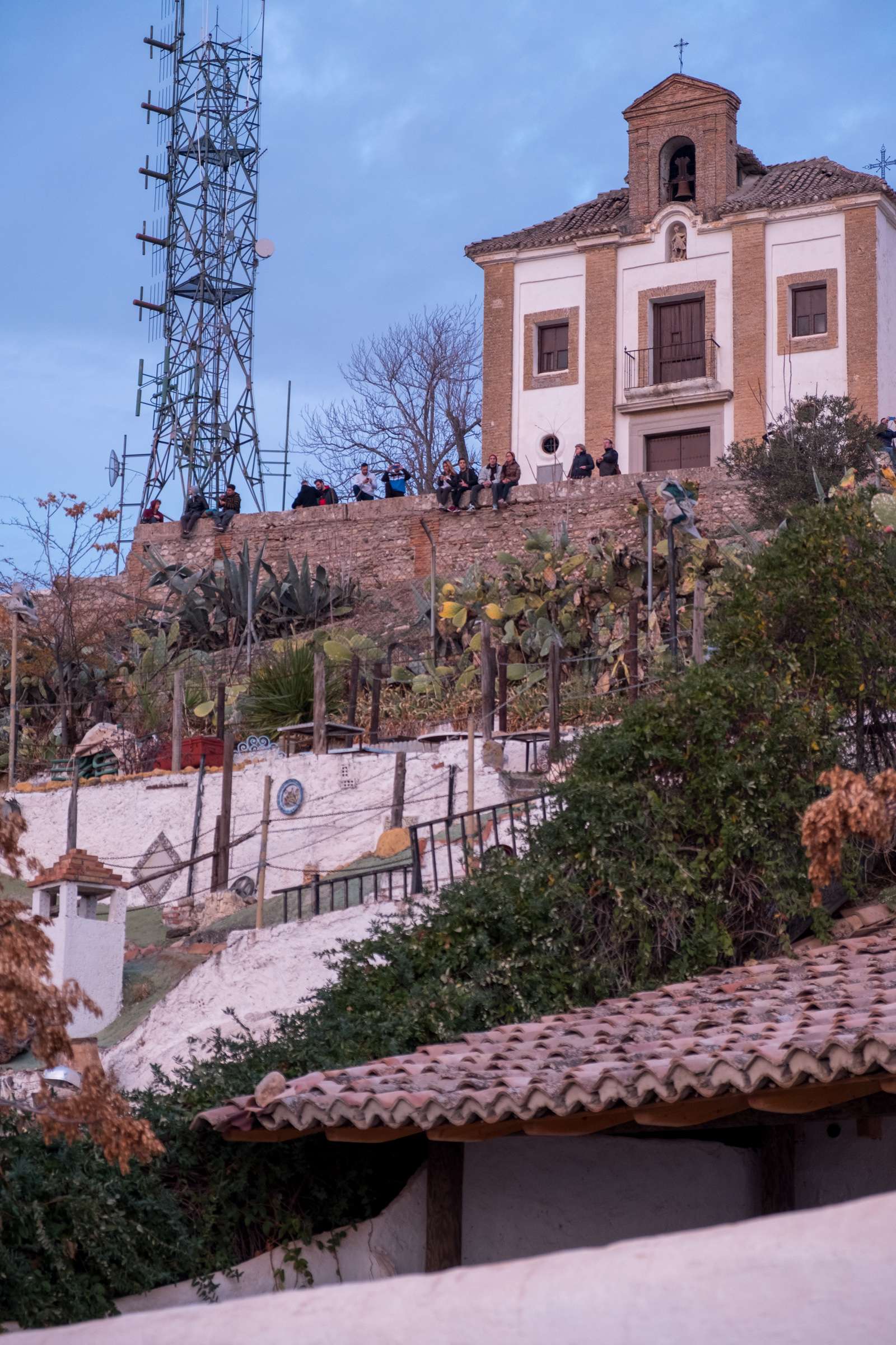 People sitting on a wall watching the sunset at Saint Michael Viewpoint, Granada
