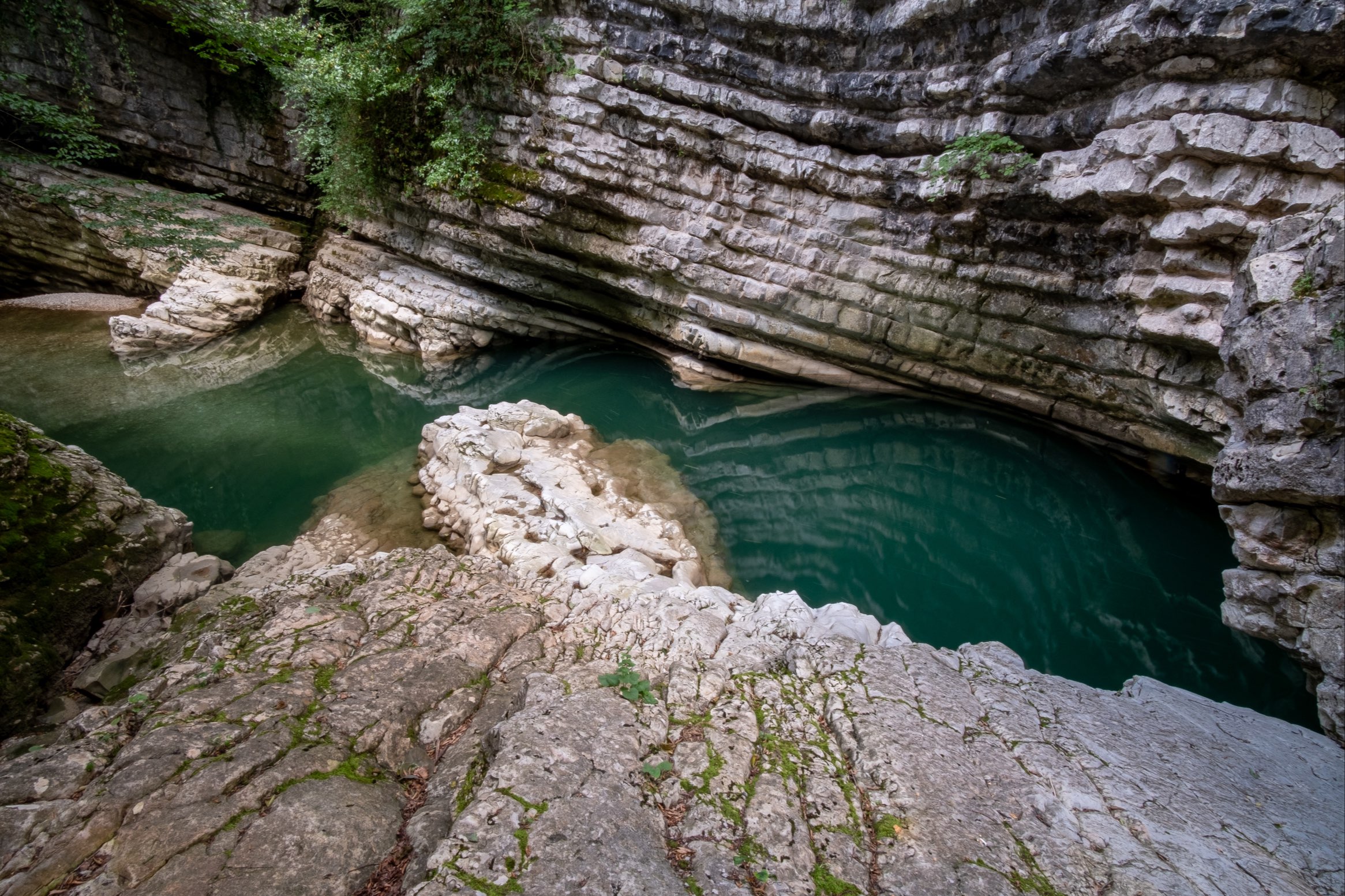 Gachedili canyon with layered rock formations and reflections in deep turquoise water