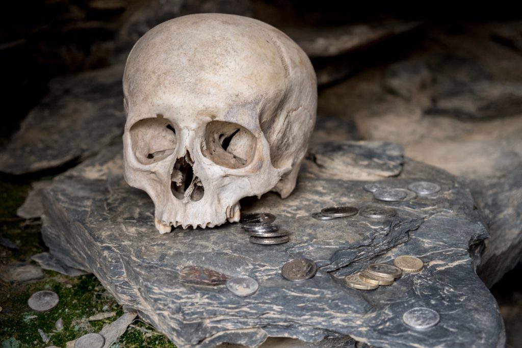 A human skull with coins in a burial tomb or vault in Mutso