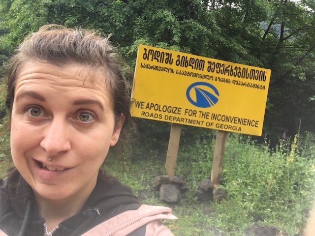 Caroline pulling a face in front of a warning sign of the roads department in Georgia