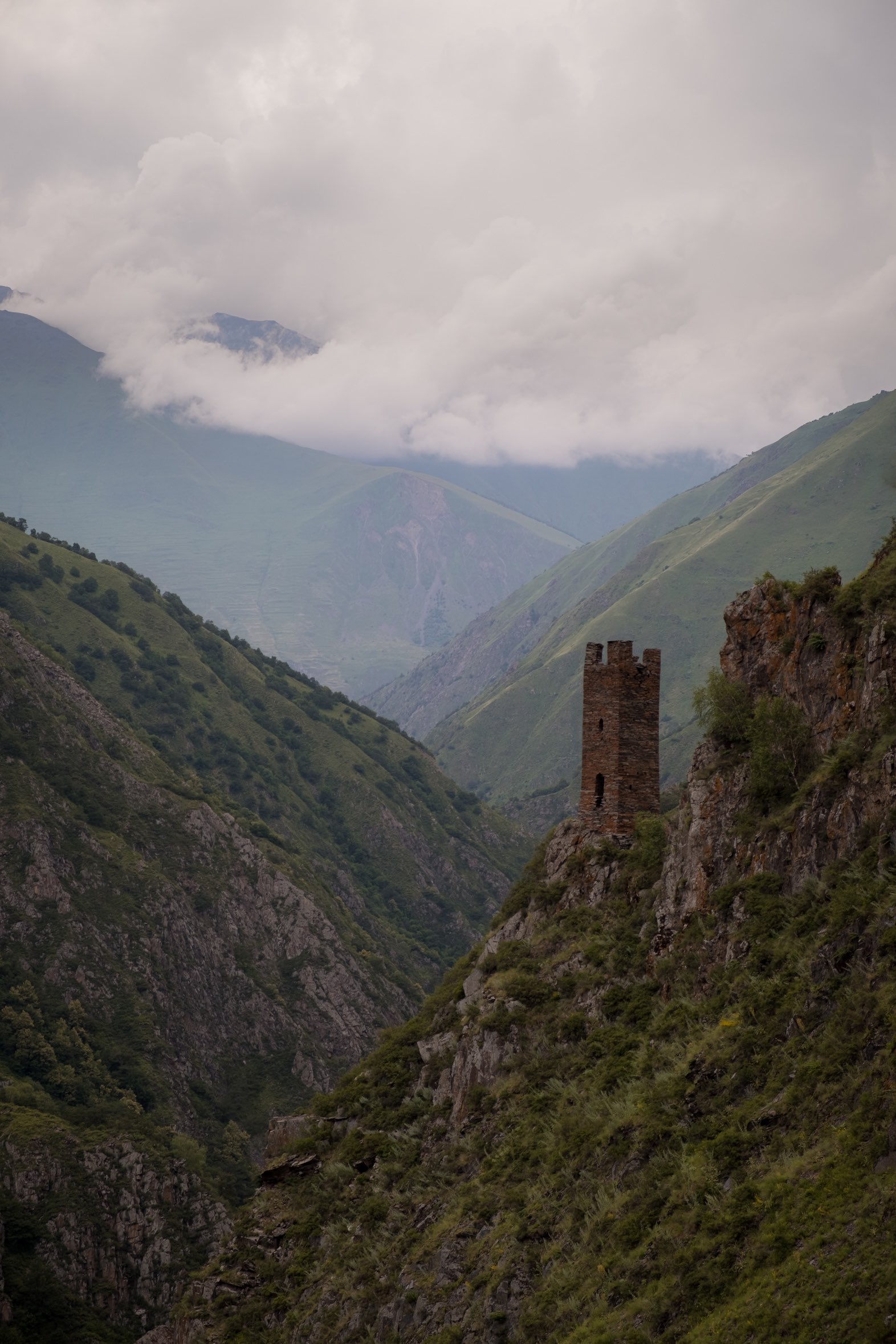 Lone watch tower of Mutso fortress against the backdrop of the Caucasus mountains