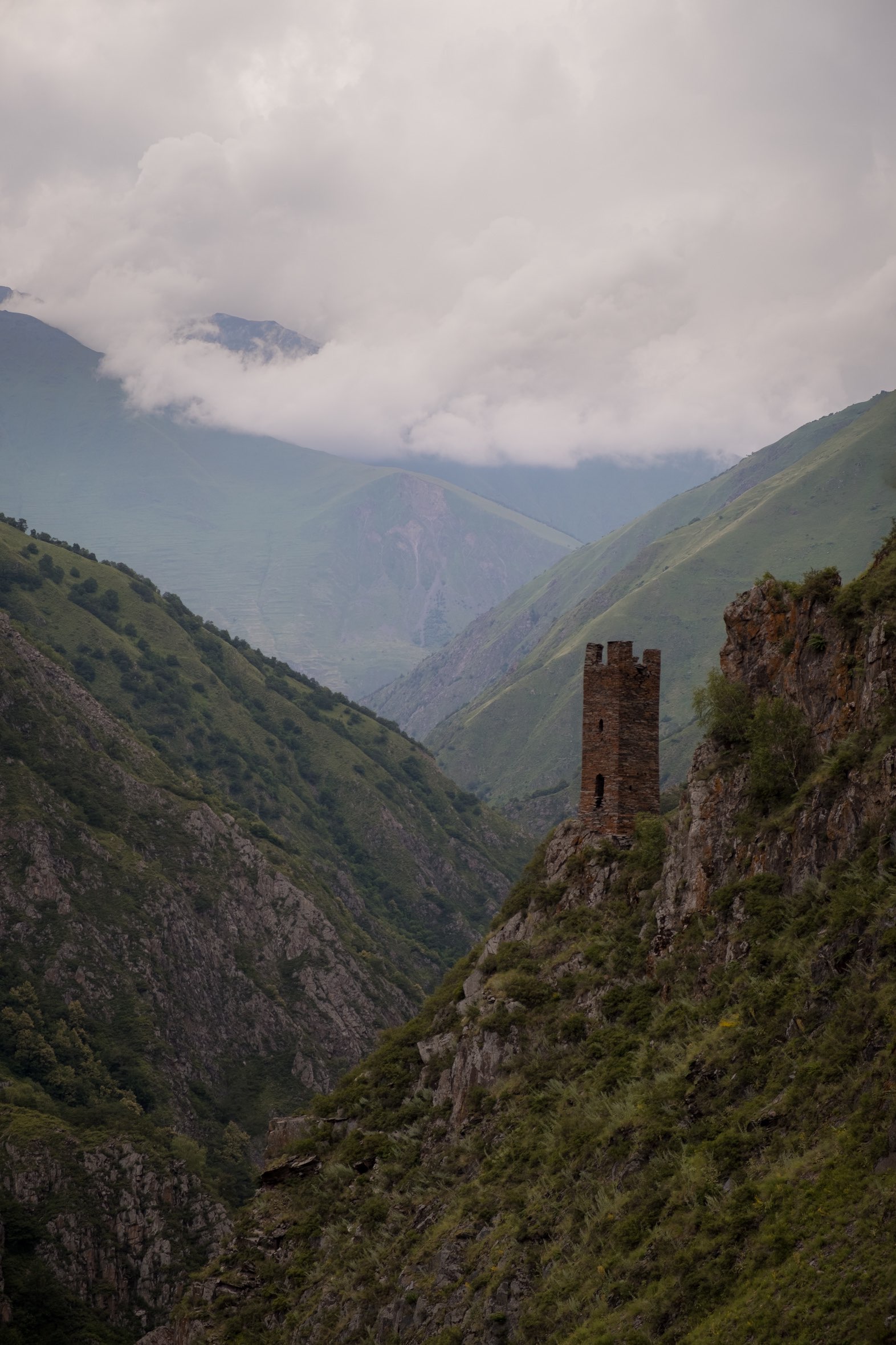 Lone watch tower of Mutso fortress against the backdrop of the Caucasus mountains