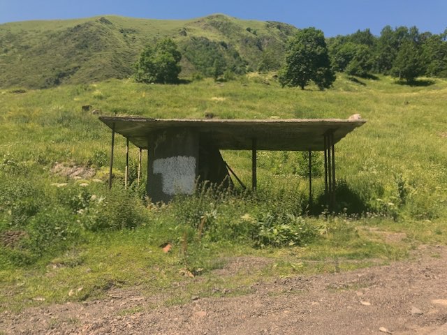 Barely standing old Soviet bus stop in the middle of the lush mountains