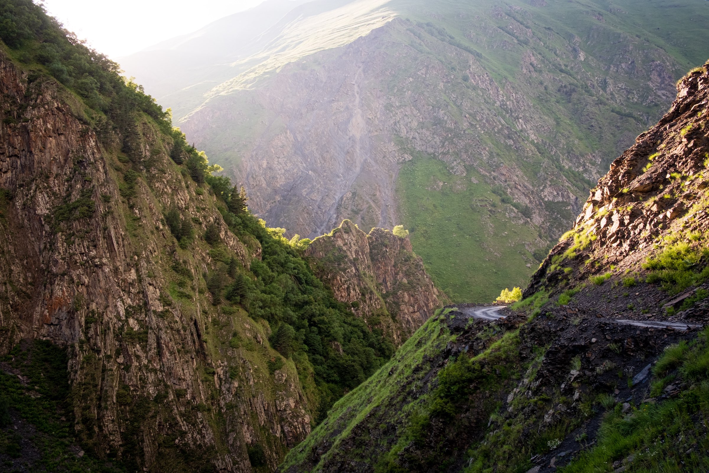 Treacherous Datvisjvari Pass, Khevsureti in golden afternoon light with wet muddy steep road