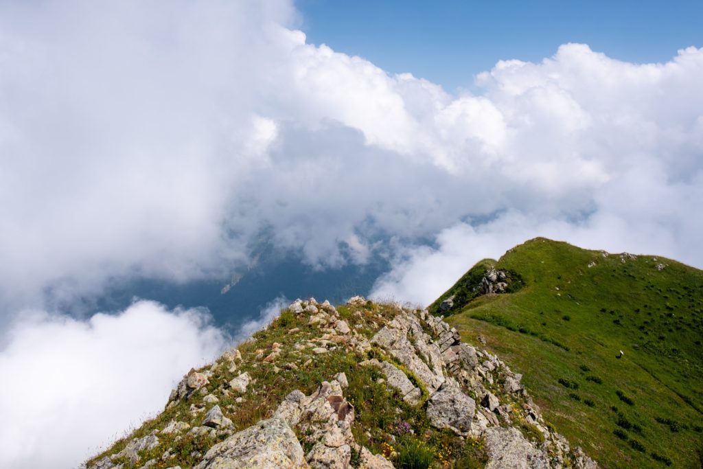 A Mountain ridge high in the Caucasus mountains peeking out above the clouds on a stormy day in Lagodekhi Protected Areas, Georgia