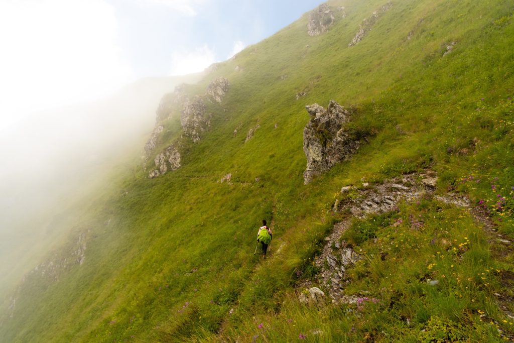 Closeup of Caroline hiking along a path on a steep grass covered mountain, high in the Caucasus mountains of Lagodekhi protected areas