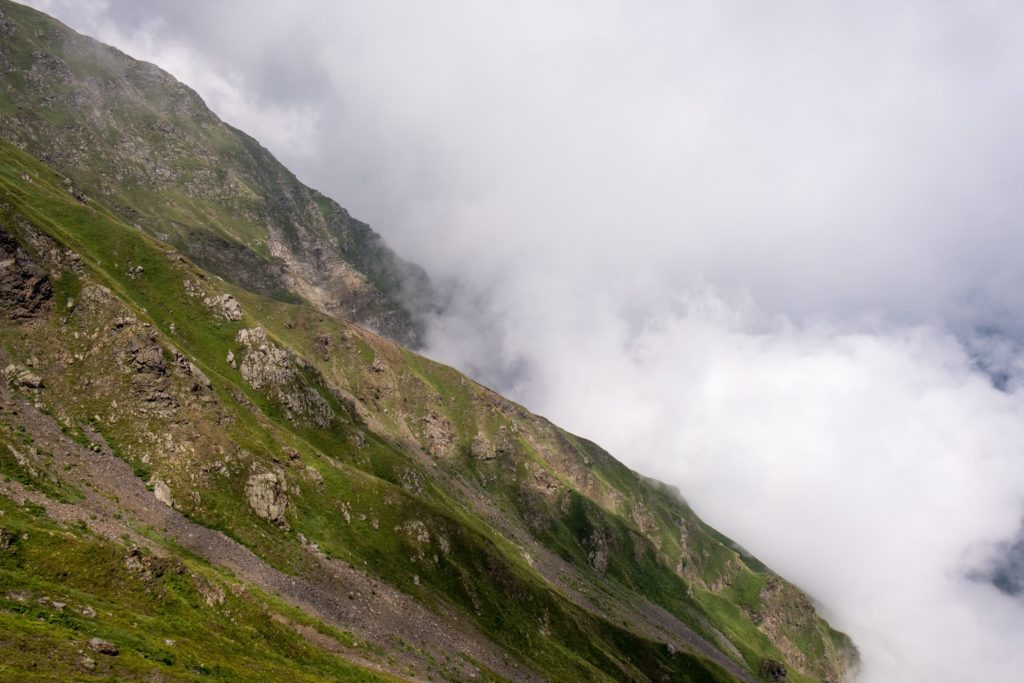 Mountain slope high in the Caucasus mountains peeking out above the clouds on a stormy day in Lagodekhi Protected Areas, Georgia