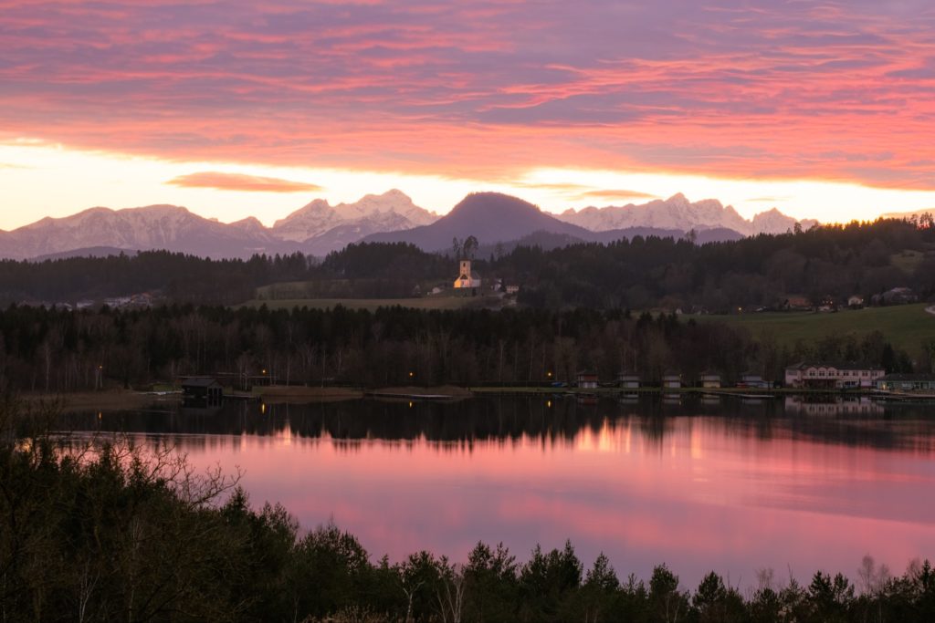Burning winter sunset reflecting in lake Längsee and the Karawanken mountains