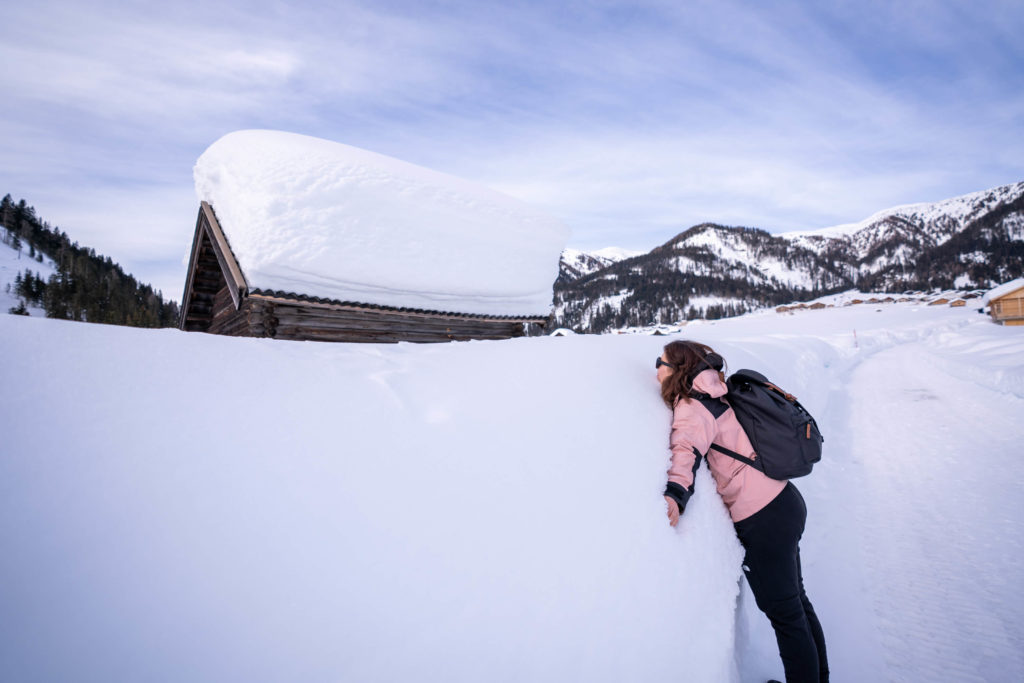 Caroline leaning on a huge wall of winter snow on a hiking path in Obertilliach, Lesachtal