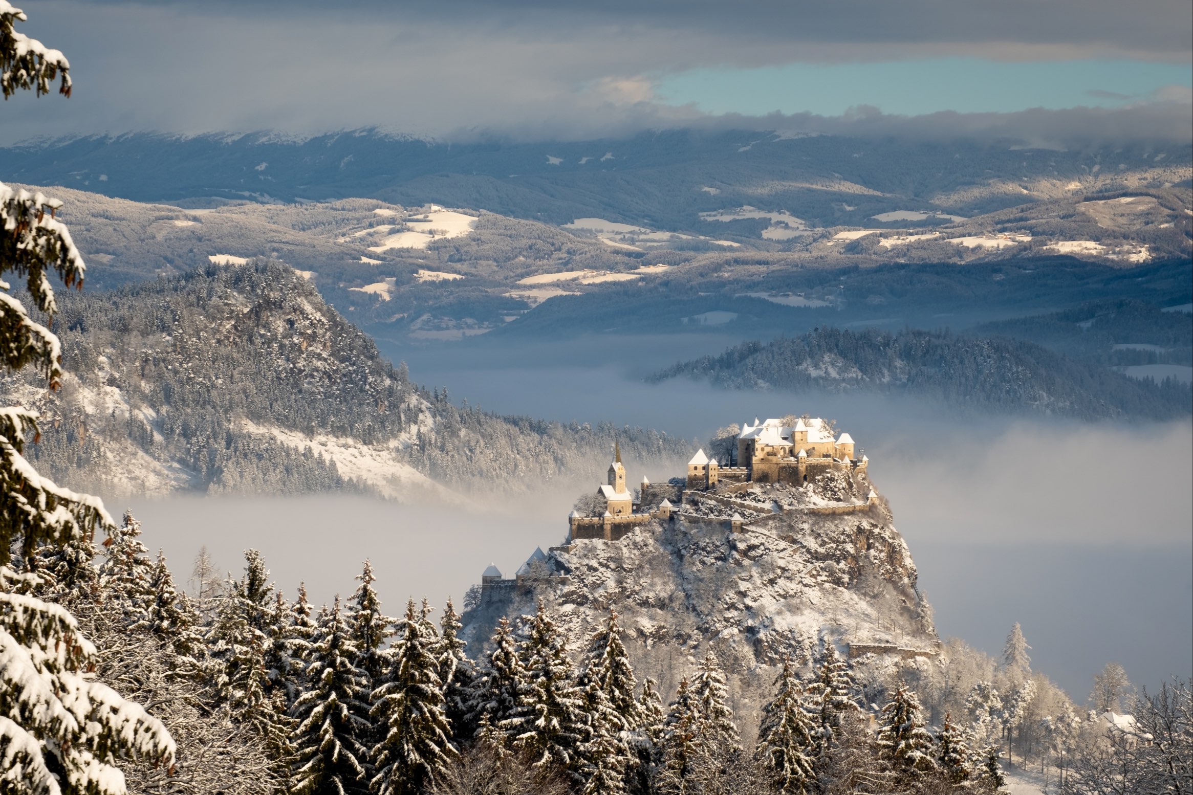 Idyllic winter morning at Hochosterwitz castle surrounded by fog and snowy mountains, Carinthia, Austria