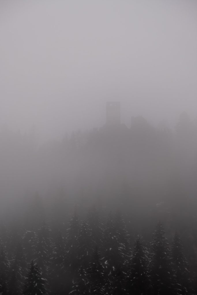 Lone spooky castle tower in the thick winter fog, Kraig, Carinthia, Austria