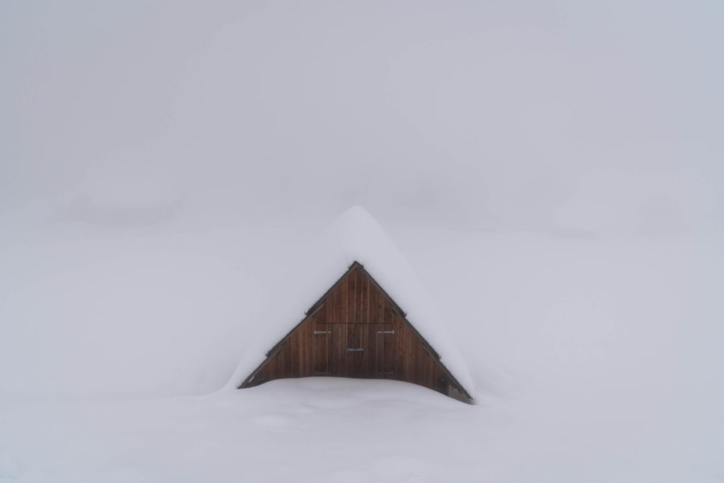 Lone wooden hut in thick winter fog and snow, Zell Pfarre, Carinthia