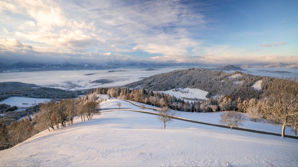 Magical winter sunrise over Magdalensberg with perfect untouched snow and thick fog covering Lower Carinthia