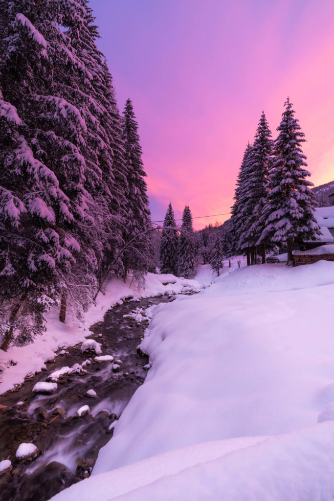 Pink and purple winter sunset over a river in the snowy landscape of Bad Kleinkirchheim, Carinthia