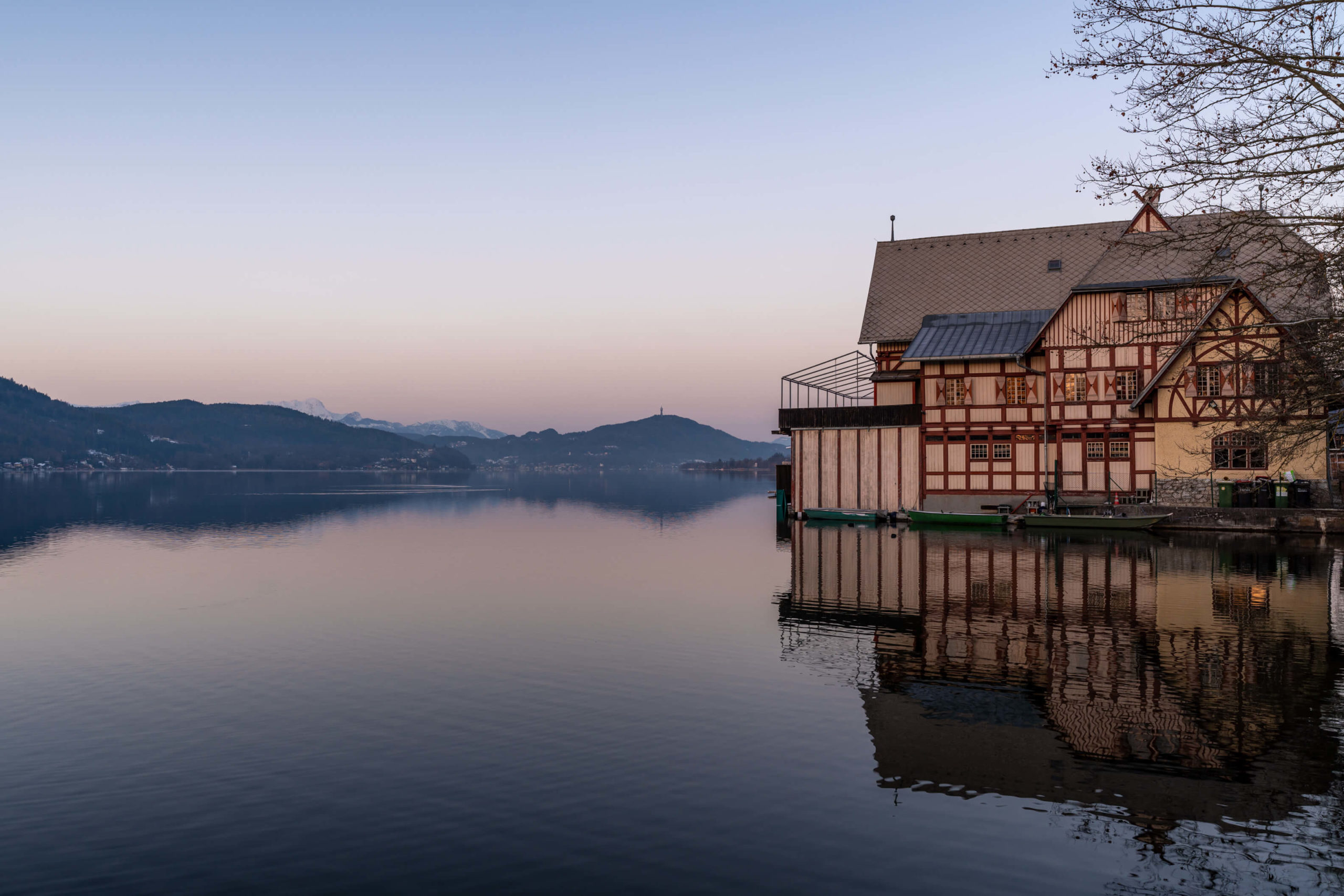 Pretty boathouse at sunrise reflecting in lake Wörthersee, Carinthia
