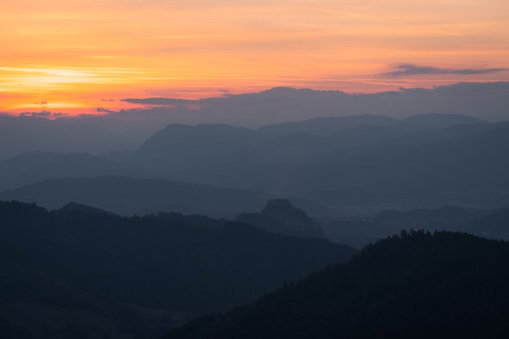 Sunset over silhouette of Hochosterwitz with layers of mountains